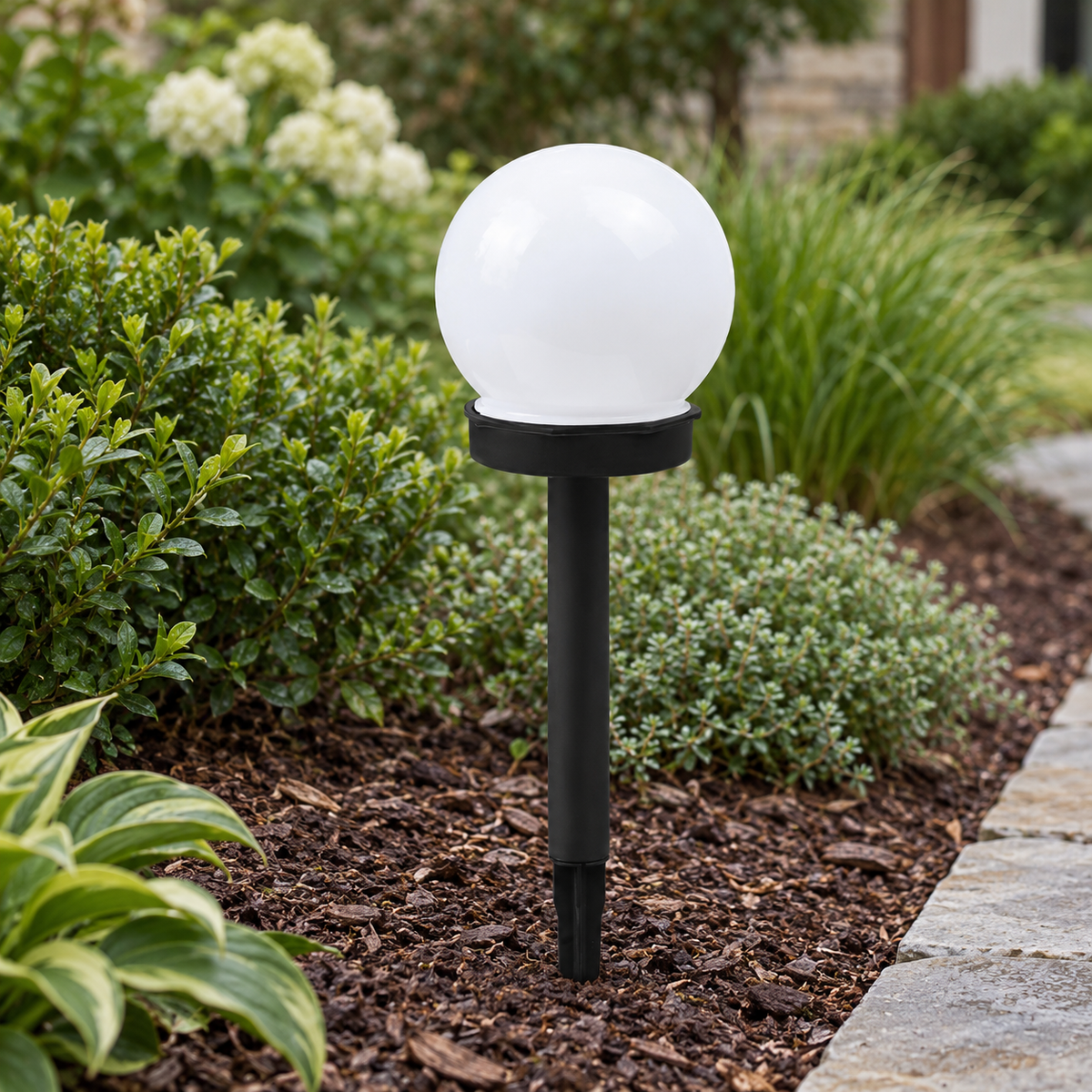 Liv solar pathway lamp with black stake and white globe in a garden border
