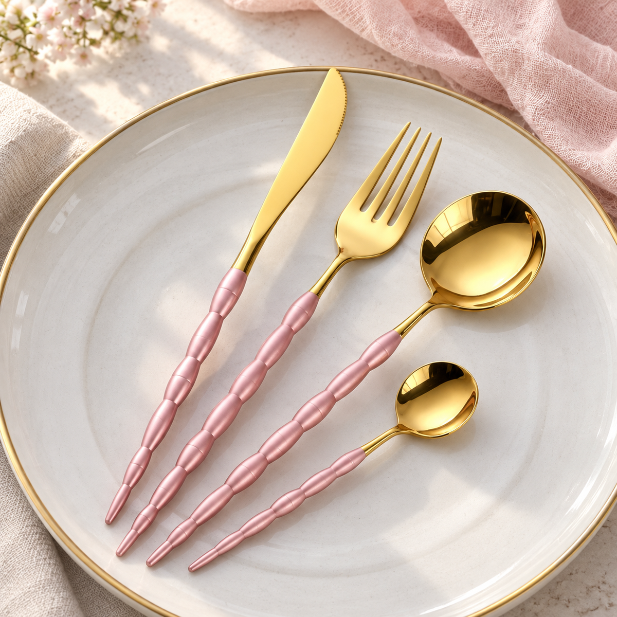 Nyland sculpted-handle cutlery set in Pink Gold on a cream stoneware plate