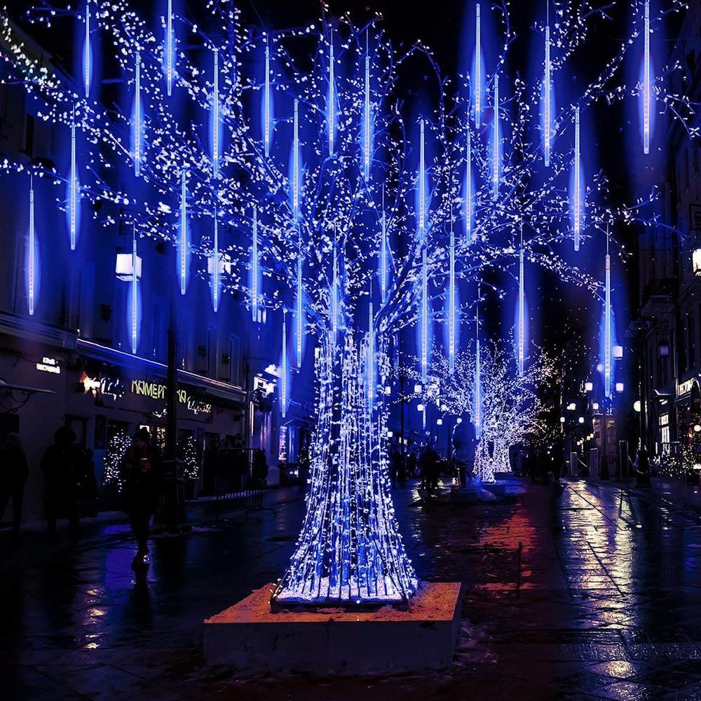 Blue LED icicle tube lights hanging from a city tree at night