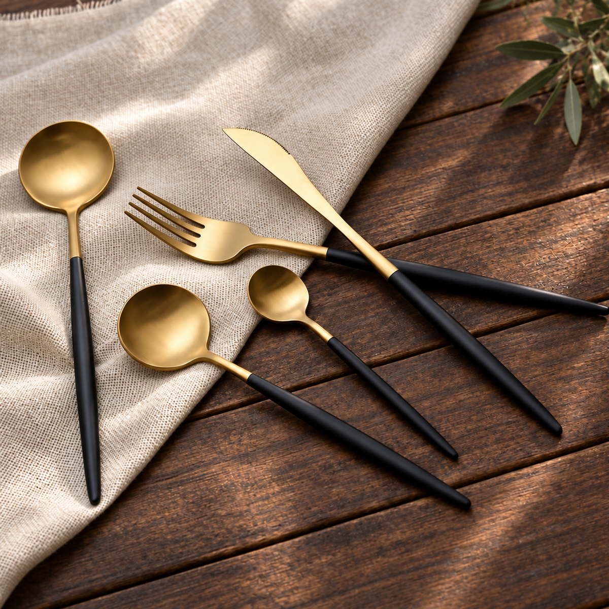 Astrid gold and black flatware arranged on dark oak with neutral linen
