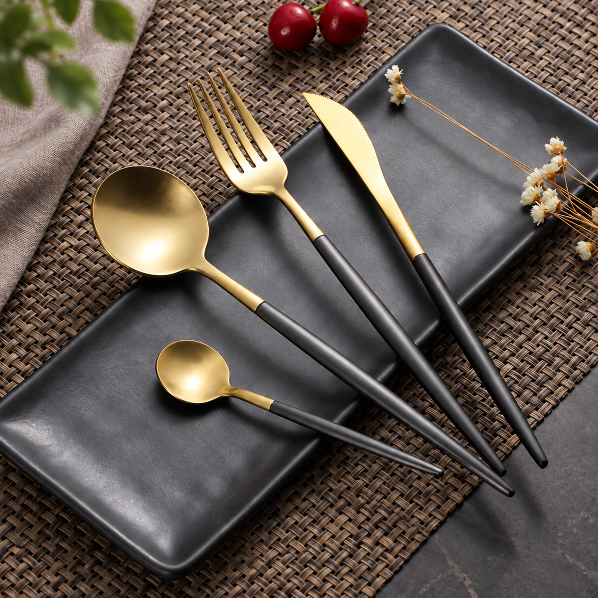 Astrid gold and black four-piece flatware set on charcoal plates