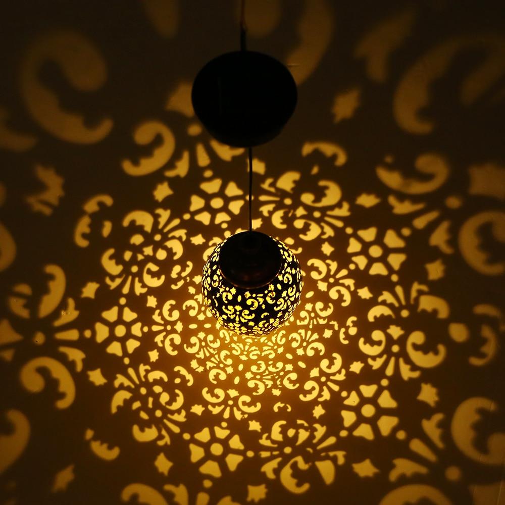 Solar droplet hanging garden lamp casting an ornate warm floral light pattern at night