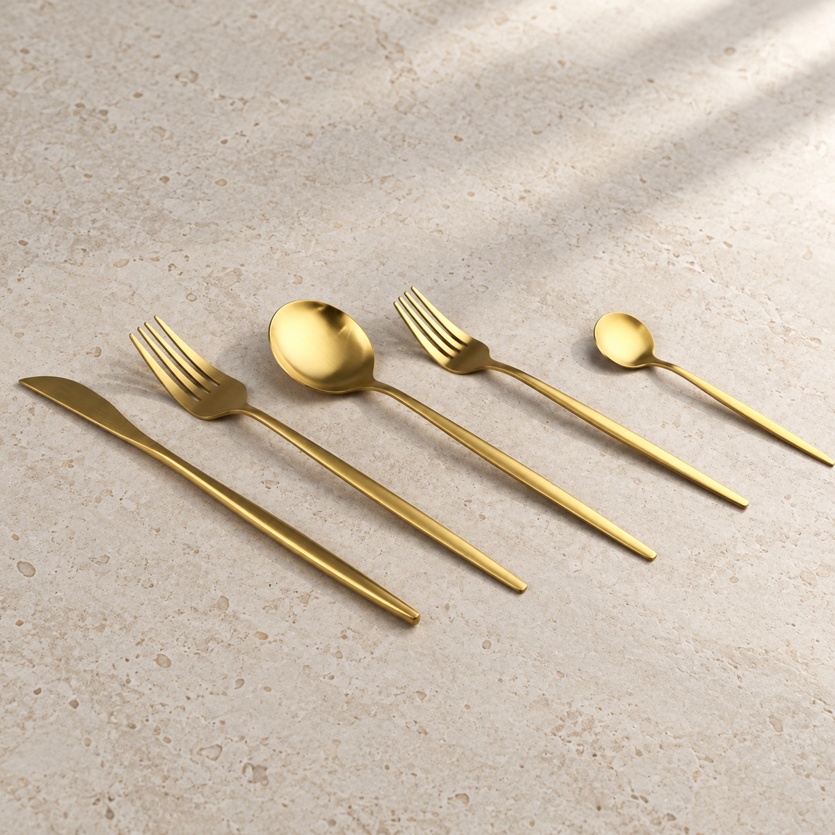 Lykke gold stainless flatware five-piece detail on ivory limestone
