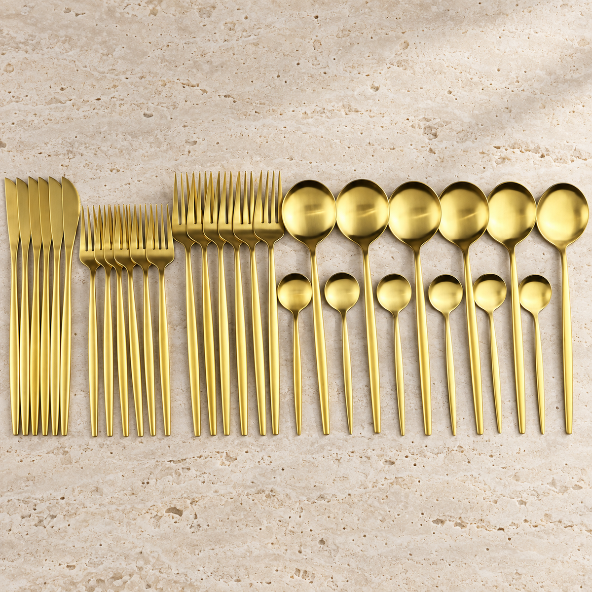 Lykke gold stainless flatware set arranged on cream travertine