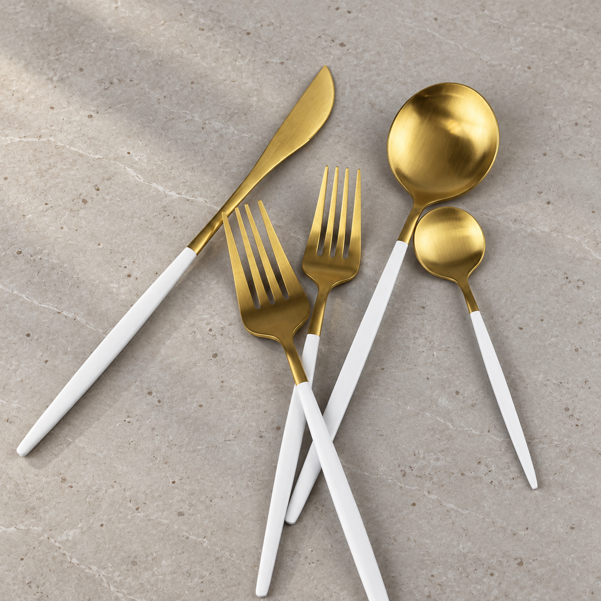 Lykke white and gold flatware five-piece detail on honed stone
