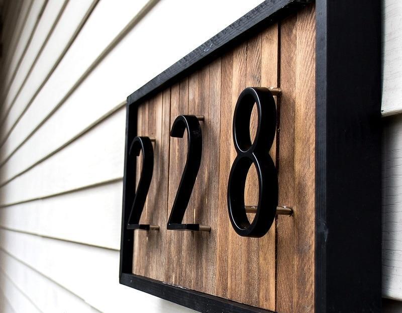 Black zinc alloy house numbers 2, 2 and 8 on a framed wood exterior plaque
