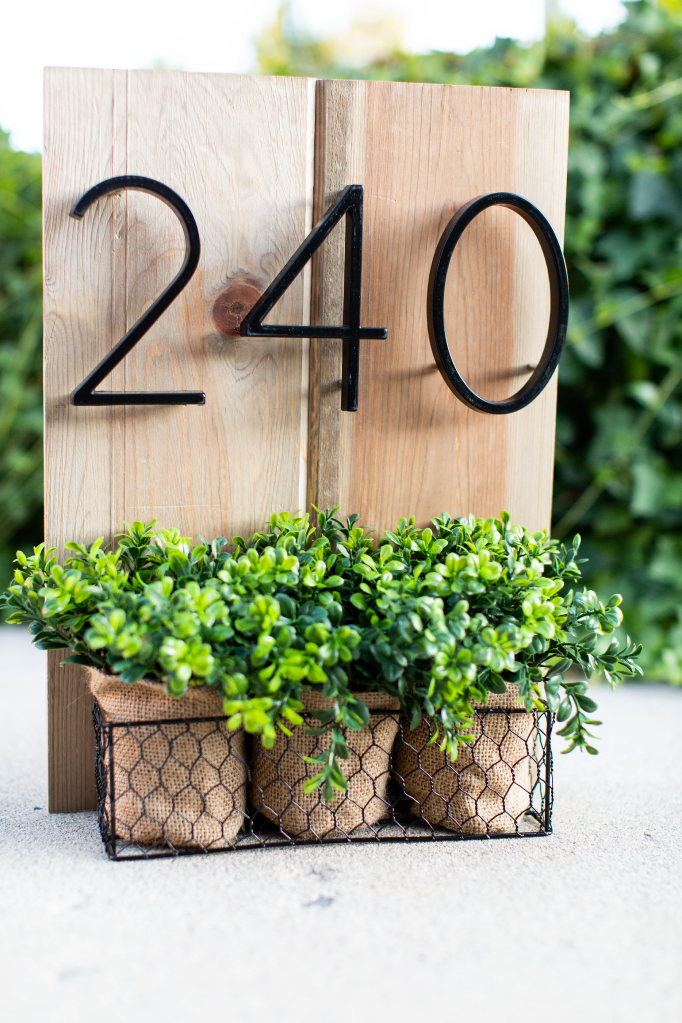 Black zinc alloy house numbers 2, 4 and 0 displayed with three planters