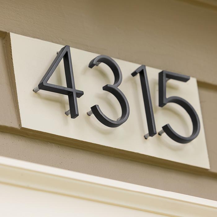 Black zinc alloy house numbers 4, 3, 1 and 5 mounted above an entry door