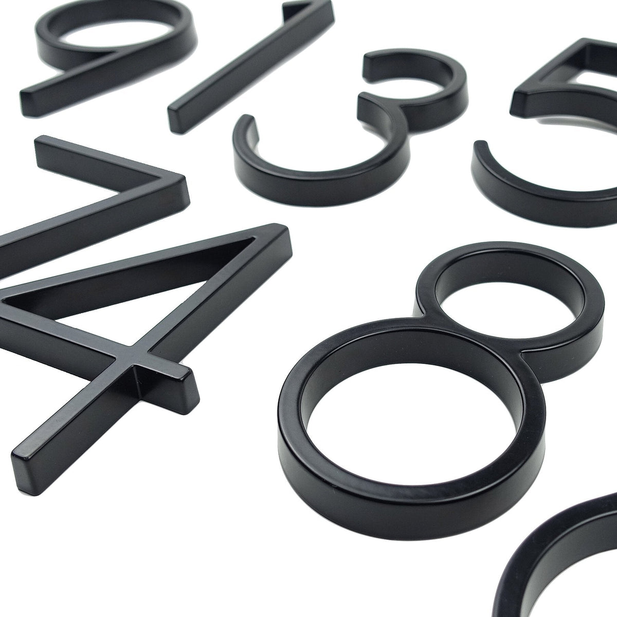 Close detail of assorted black zinc alloy house numbers on a white background
