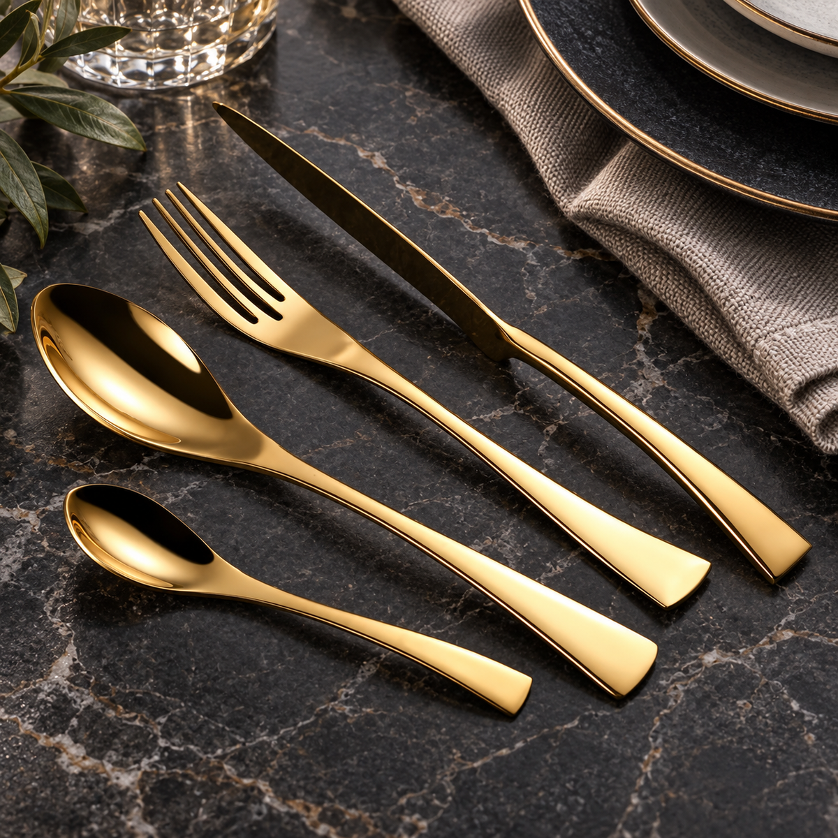 Vidar gold metal cutlery set with knife, fork, tablespoon and teaspoon on a dark stone table