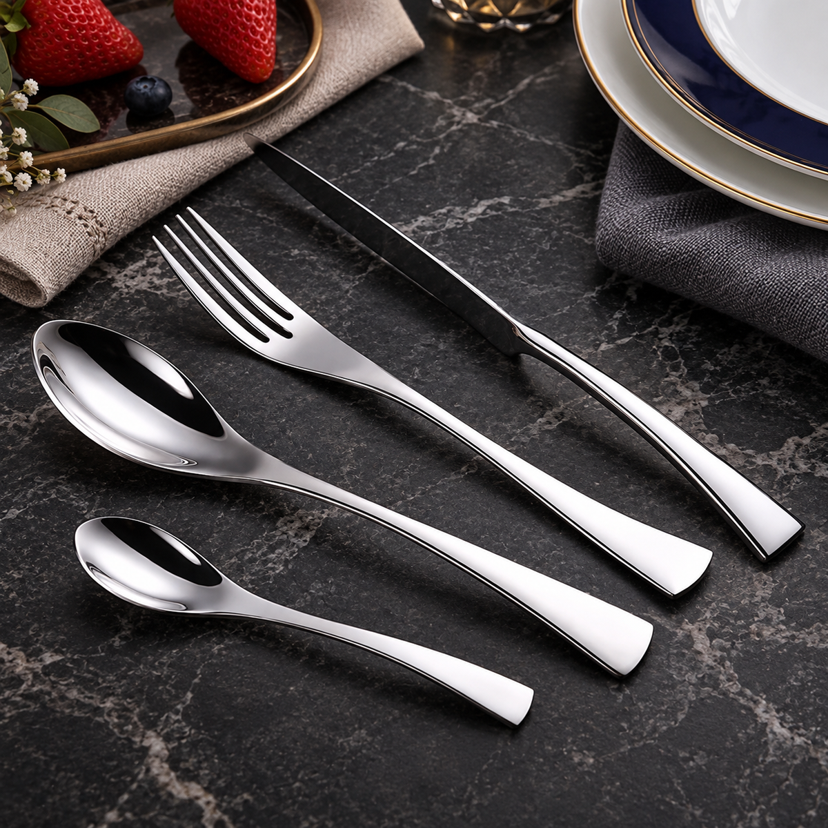 Vidar silver metal cutlery set with knife, fork, tablespoon and teaspoon on a dark stone table