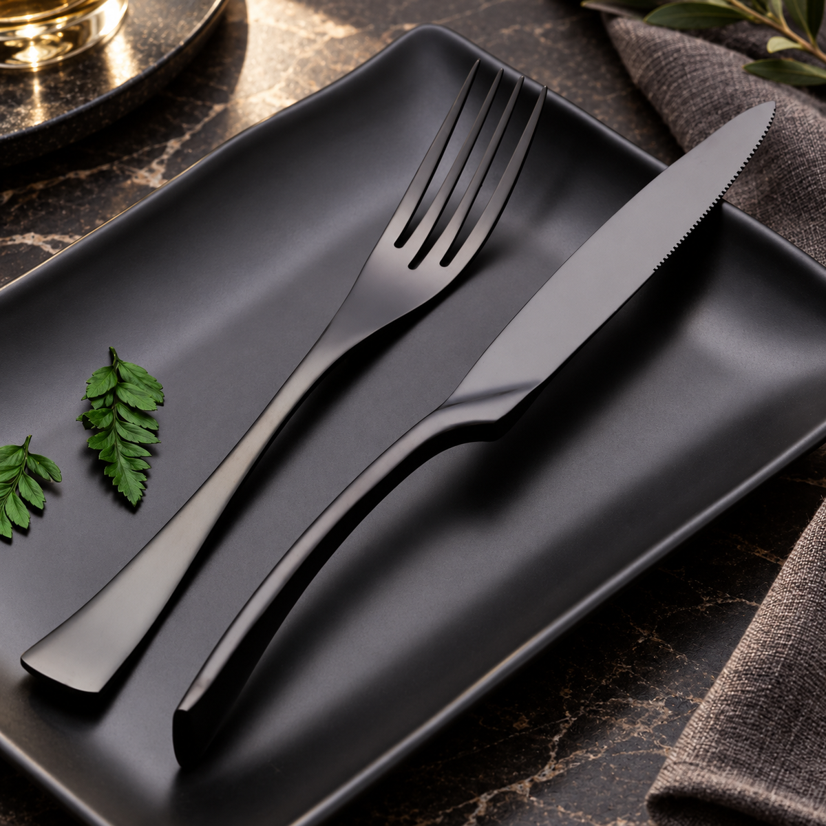 Vidar black metal fork and knife arranged on a matte black plate
