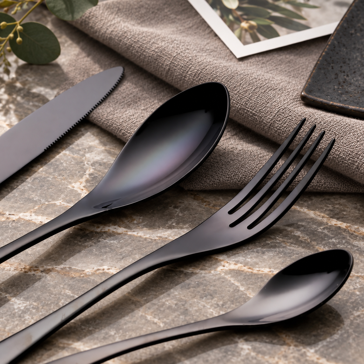 Vidar black metal cutlery close-up with knife, fork and spoons on a stone table