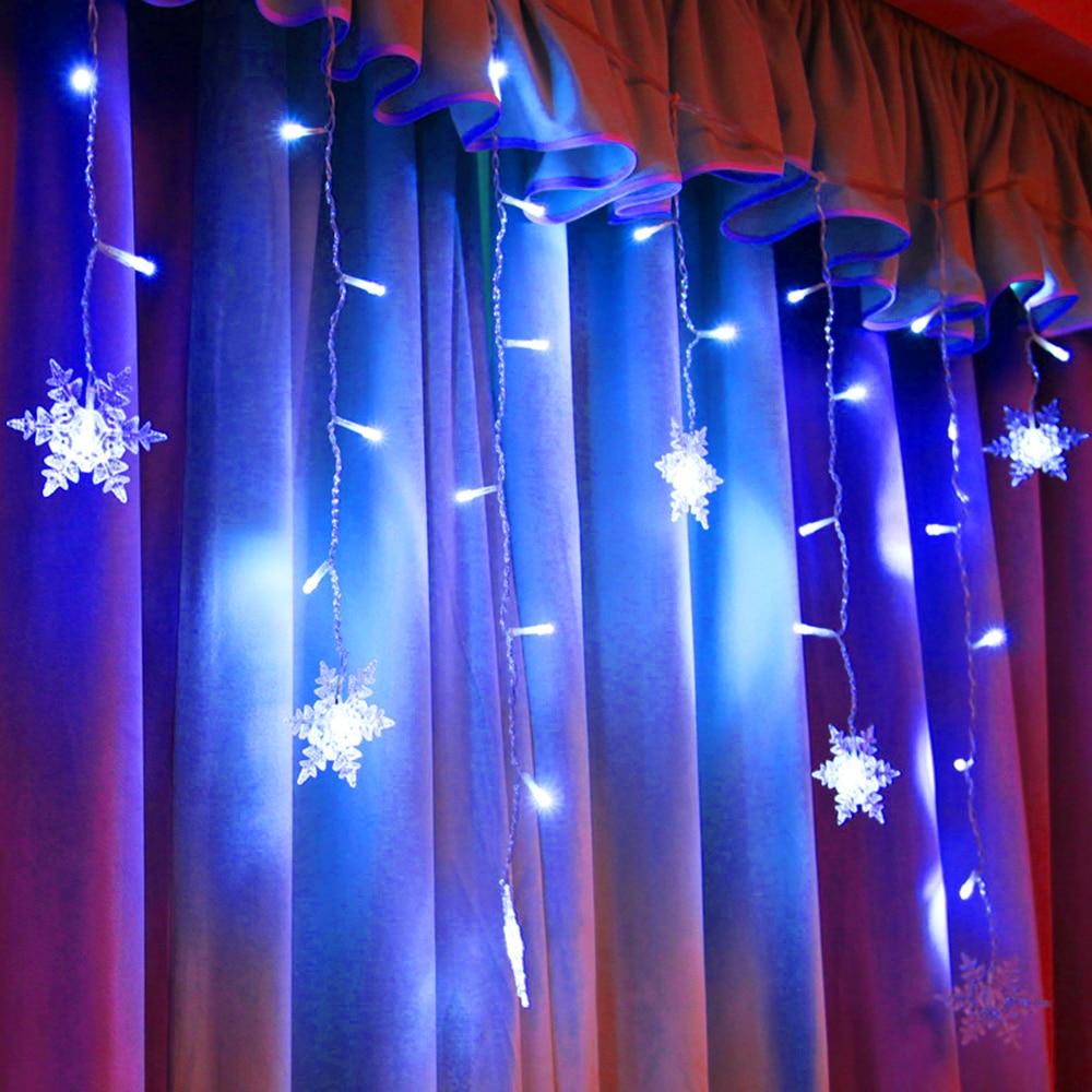 Torun snowflake LED string lights glowing blue against layered curtains