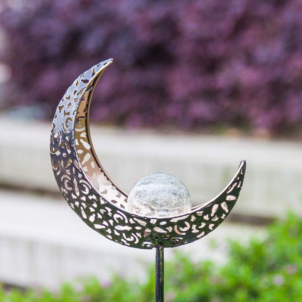 Solar crescent moon garden stake with silver filigree crescent and clear glass orb outdoors