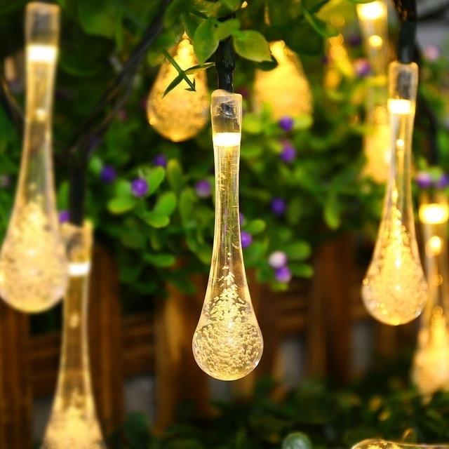 Sigrid warm white solar droplet string lights glowing in garden foliage