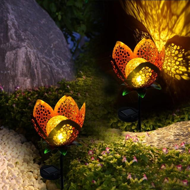 Idun gold flower stake lights glowing among garden plants and stone