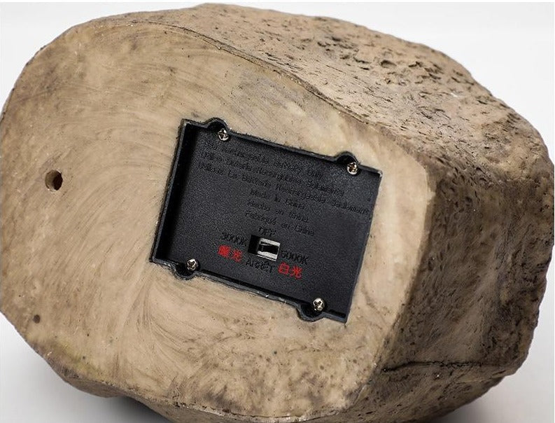 Stone-effect solar garden light underside with battery cover, switch and stone texture