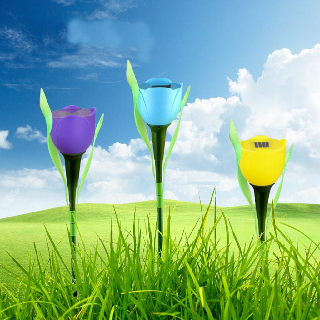 Purple, blue and yellow solar tulip garden stake lights standing in grass under a blue sky
